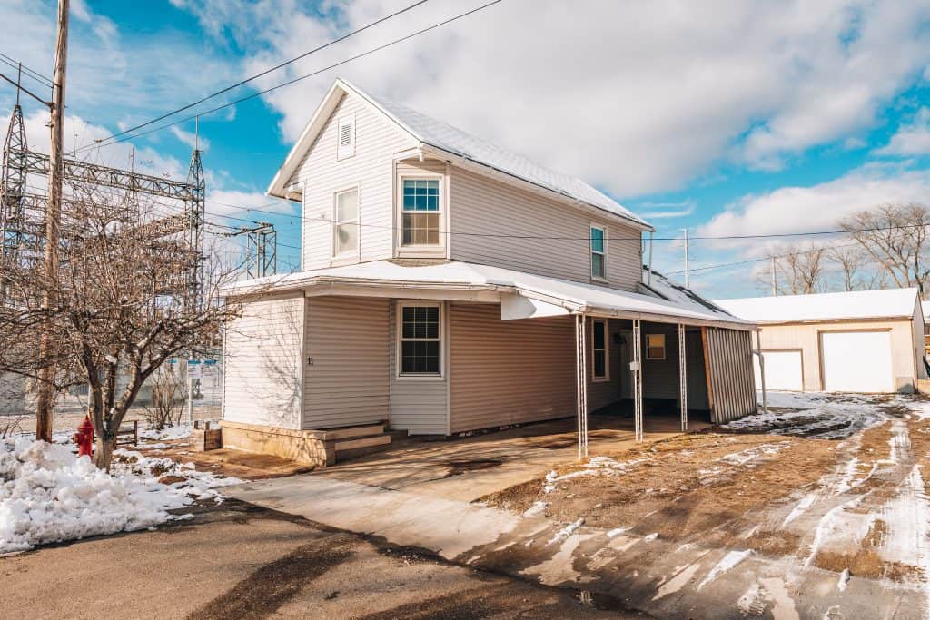Two-story home at 11 Sherman Street, Dennison, Ohio featuring a covered car port and paved driveway.
