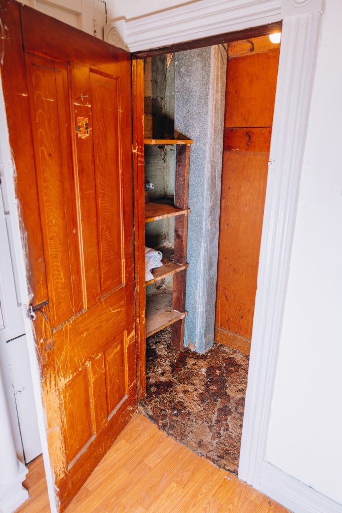 Closet providing basement access at 11 Sherman Street, Dennison, Ohio with wood shelving and ductwork.