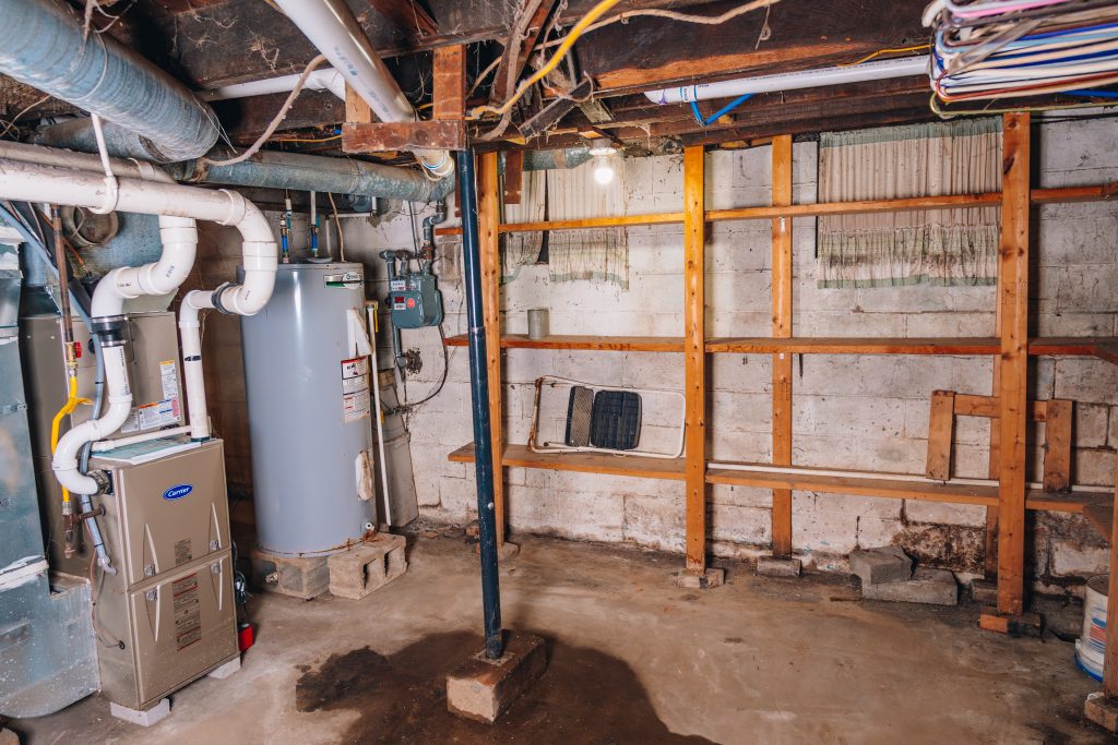 Basement utility area at 11 Sherman Street, Dennison, Ohio with furnace, water heater, and shelving.