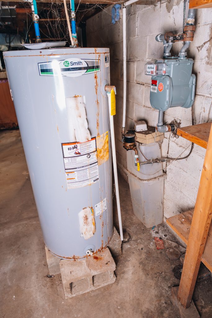 Basement water heater and gas meter at 11 Sherman Street, Dennison, Ohio with exposed piping.