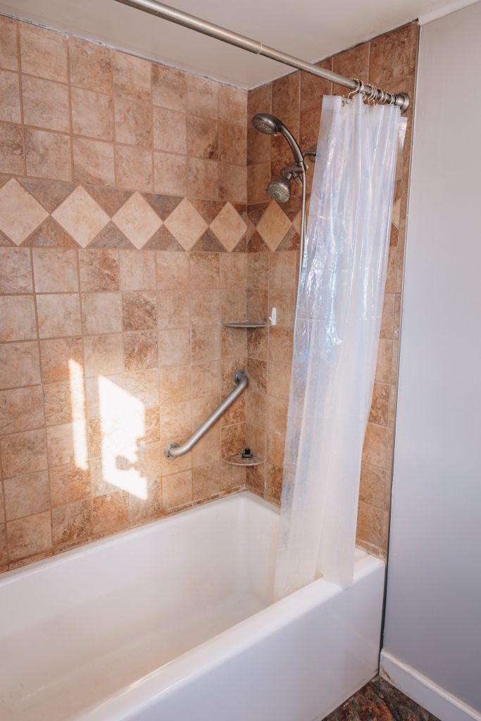 First-floor bathroom at 11 Sherman Street, Dennison, Ohio remodeled in 2022 featuring bathtub with tile surround and grab bar.
