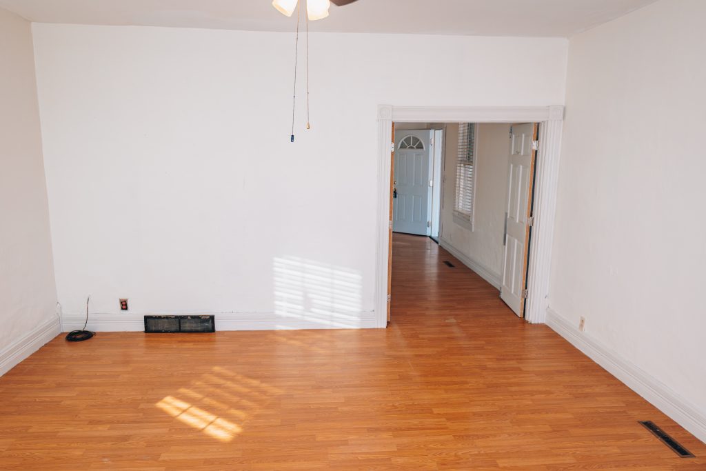 Wide view of first-floor bedroom at 11 Sherman Street, Dennison, Ohio with wood-look flooring and doorway to hall, remodeled in 2019