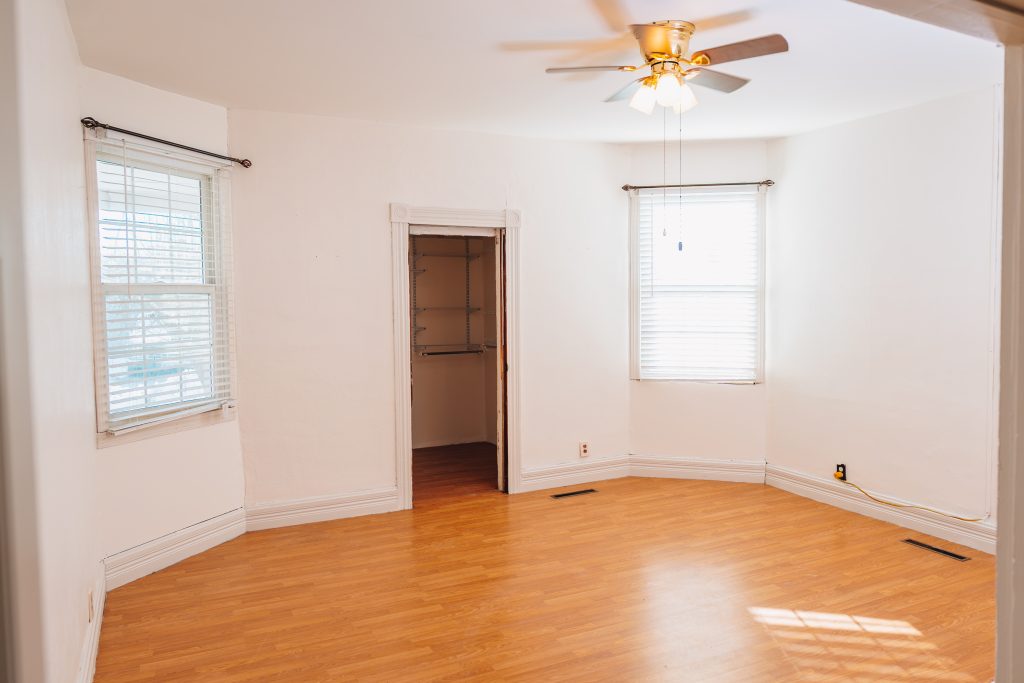 First-floor bedroom at 11 Sherman Street, Dennison, Ohio with walk-in closet, two windows, ceiling fan, and wood-look flooring, remodeled in 2019.