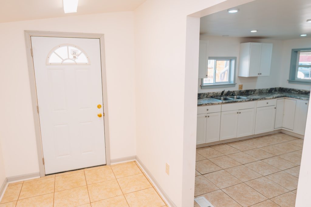 First-floor laundry room at 11 Sherman Street, Dennison, Ohio with tile flooring and view into kitchen.