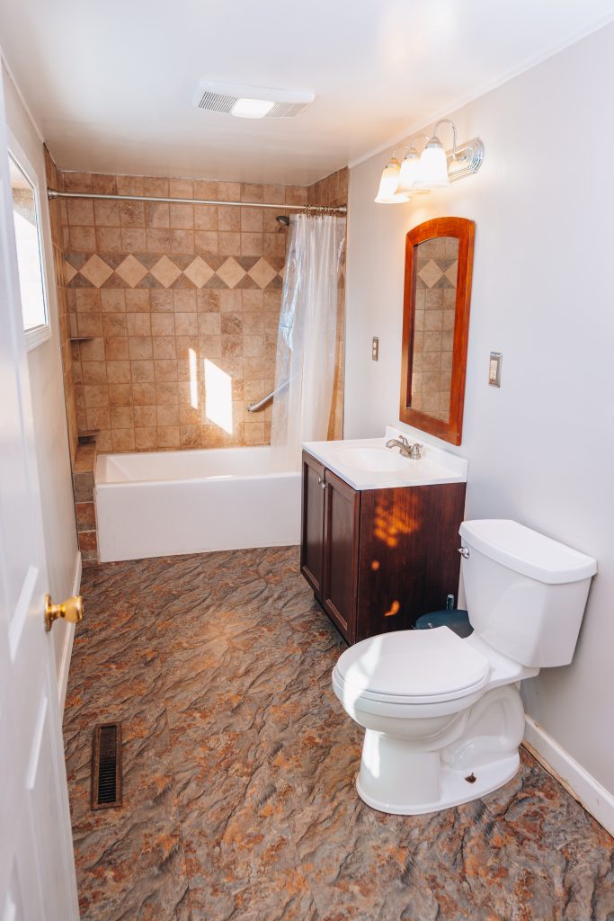 Full view of first-floor bathroom at 11 Sherman Street, Dennison, Ohio remodeled in 2022 featuring tub, vanity, and toilet.