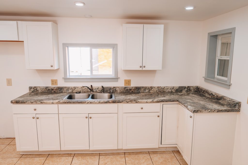Kitchen sink area at 11 Sherman Street, Dennison, Ohio with granite countertops and white cabinets.