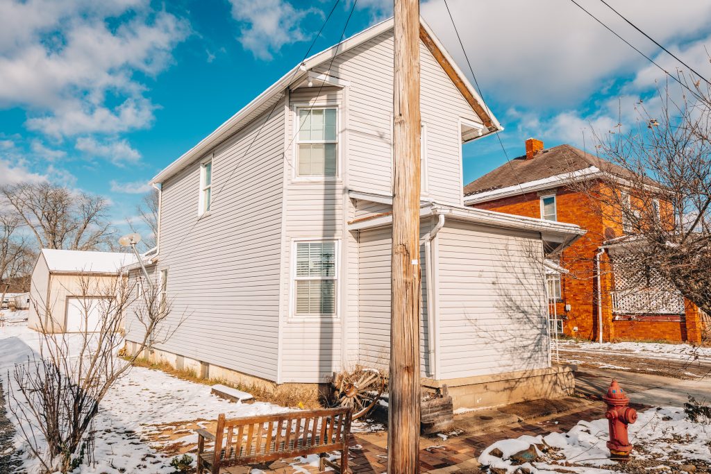 Side exterior view of two-story home at 11 Sherman Street, Dennison, Ohio with beige siding and snow-covered yard.