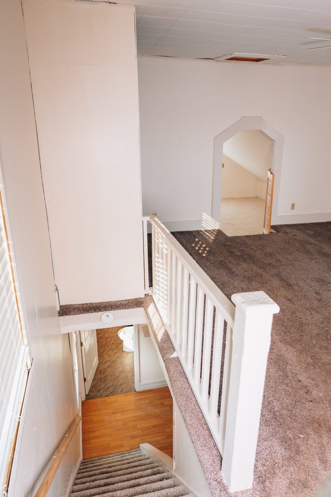 View from staircase to upstairs landing at 11 Sherman Street, Dennison, Ohio showing carpeted stairs and railing.
