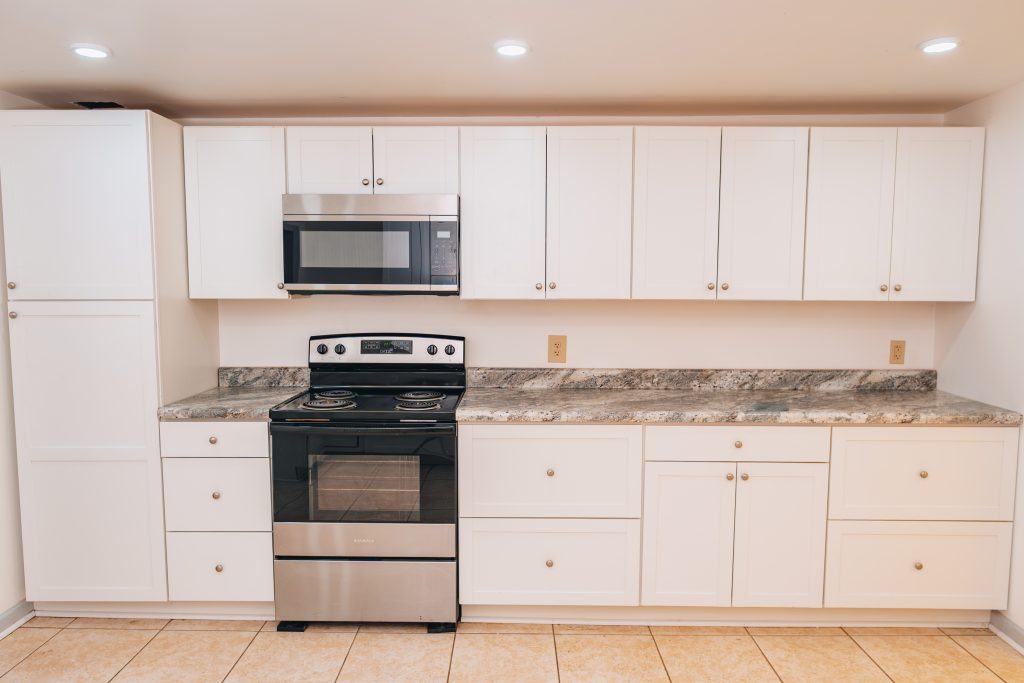 Updated kitchen at 11 Sherman Street, Dennison, Ohio featuring stainless steel stove and microwave, white cabinets, and granite countertops.