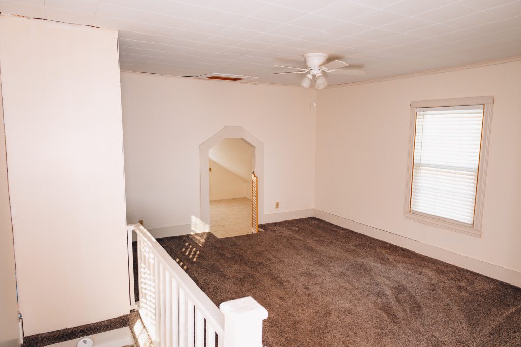 Upper landing bedroom at 11 Sherman Street, Dennison, Ohio with archway leading to another bedroom.