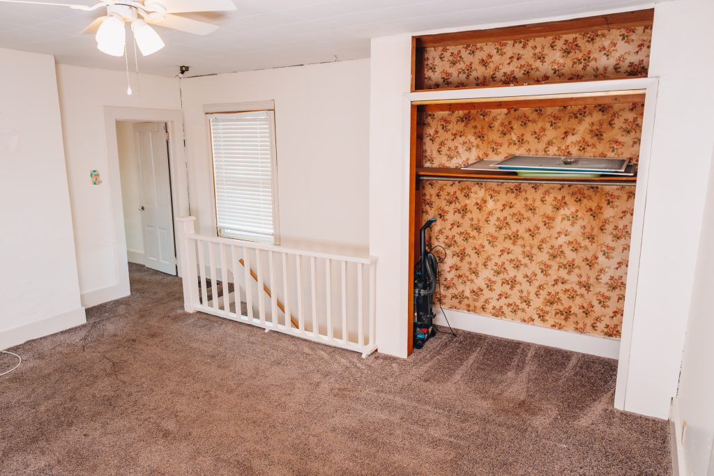 Wide view of upstairs bedroom at 11 Sherman Street, Dennison, Ohio showing open closet, staircase railing, and ceiling fan