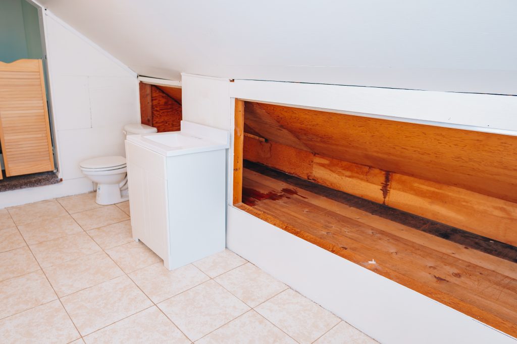 Upstairs half bath at 11 Sherman Street, Dennison, Ohio with vanity, toilet, and built-in storage under sloped ceiling.